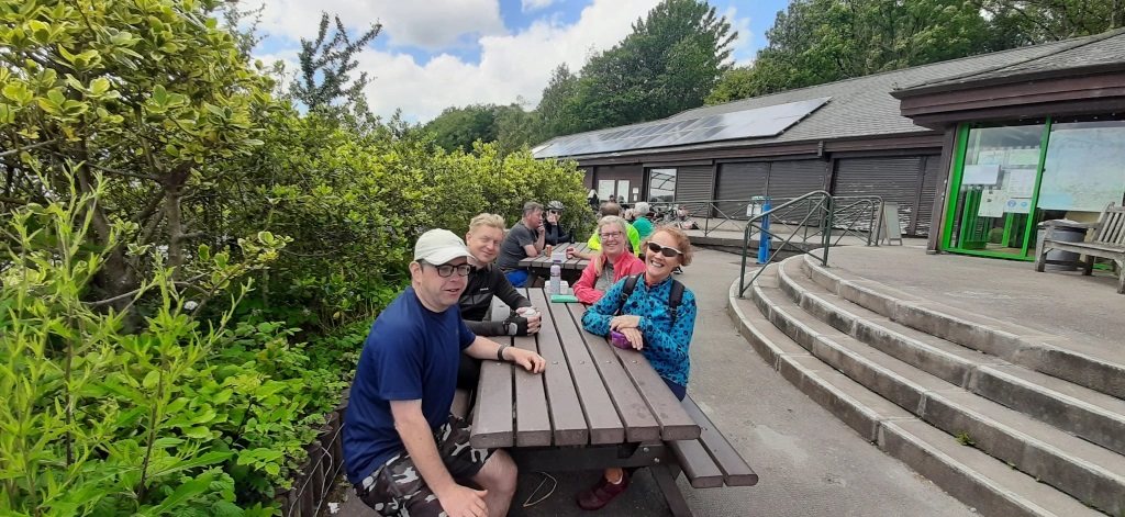 A group of cyclists sitting at a picnic table